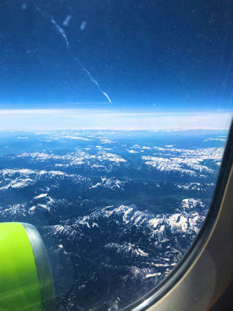 View on the mountains with snowy peaks from airplane window. Vertical photo. Special dotted photo effect.の写真素材