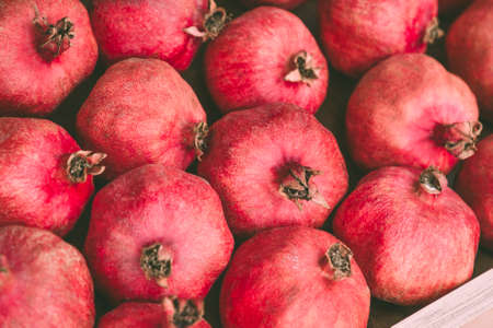 Ripe juicy red pomegranates on the wooden shelf. Harvest and sell of organic fresh fruits.の写真素材
