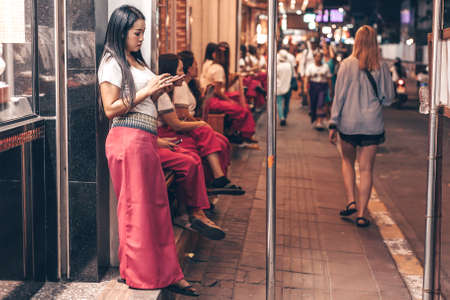 Thai lady stands on the walking street. Nightlife of Thailand, Pattaya 2019-12-23.のeditorial素材