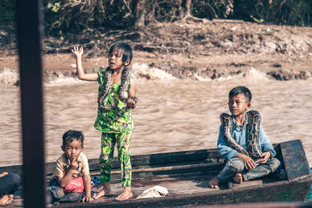 Children with large python snakes on the wooden boat at the Tonle Sap lake in Cambodia 2019-12-27. The floating village on the water.のeditorial素材