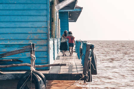 Little girls near the only school in a floating village on the lake Tonle Sap in Cambodia 2019-12-27.のeditorial素材