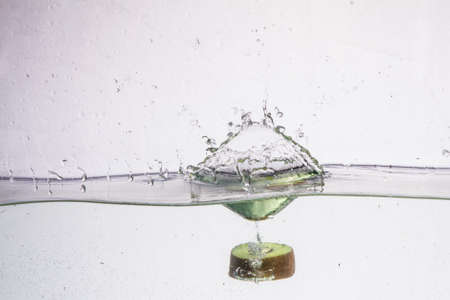 Kiwifruit slice in water with bubbles on white backgroundの写真素材