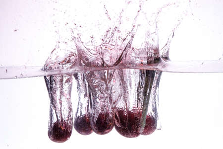 close-up of cherry in pure water with bubbles. splash of water and fruit floating in it.の写真素材