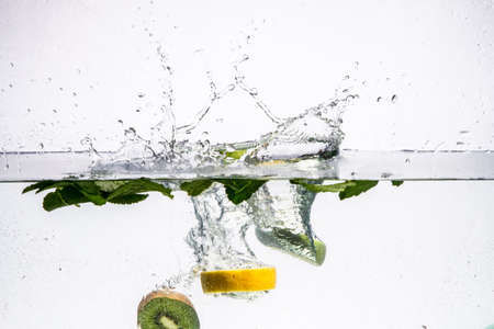 A background of bubbles forming in blue water after fruits is dropped into it.