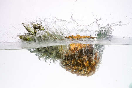 Fresh pineapple jumping into waterの写真素材