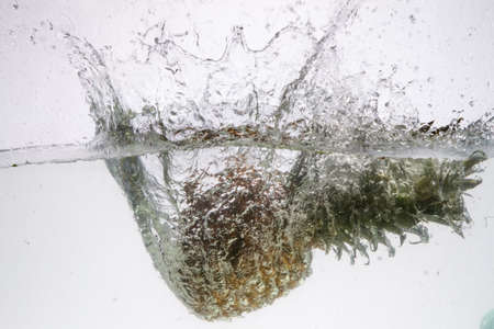 Fresh pineapple jumping into waterの写真素材