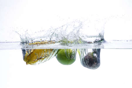 three peppers falling in water. splash of water and fruit floating in it.