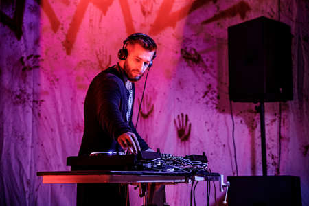 KHARKIV, UKRAINE - OCTOBER 26, 2019: DJ stands behind the music console and mixes music.
