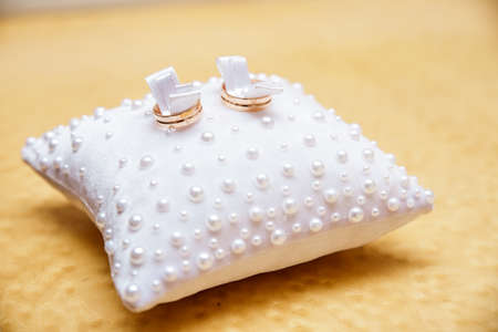 Wedding rings on a white small pillowの写真素材