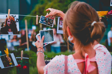 Family photos hanging over spring flowersThe girl hangs photos on a rope. Photo exhibition.のeditorial素材