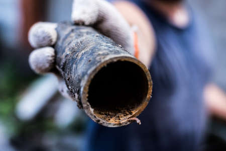 A worker holds in his hands piece of a metal pipe cut offの写真素材