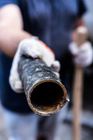A worker holds in his hands piece of a metal pipe cut offの写真素材