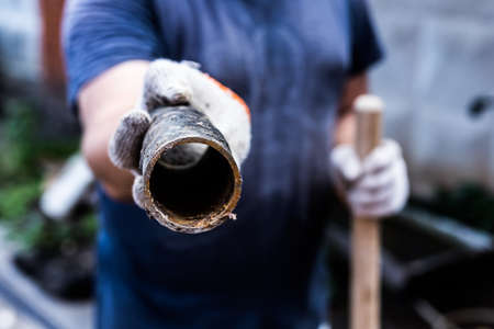 A worker holds in his hands piece of a metal pipe cut offの写真素材