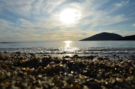 beautiful sunset on the sea with pebbles on the beachの写真素材