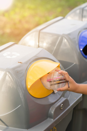 Woman hand throwing plastic glass into recycling bin, Concept of environmental.の写真素材