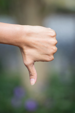 Thumb down female hand sign on nature background.の写真素材