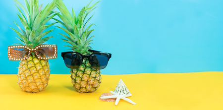 Pineapple wearing sunglasses and starfish on a yellow and blue background. Summer and fashion concept.の写真素材