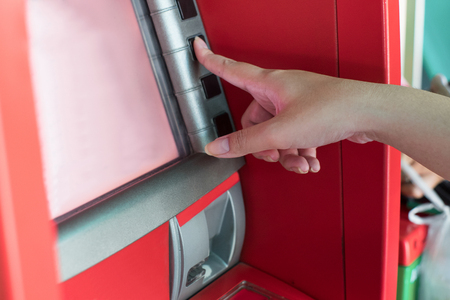 Hand press bottom on ATM bank machine to withdraw moneyの写真素材