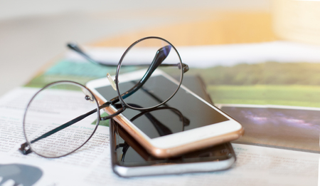 Glasses and smart phone on a book at coffee shop.の写真素材