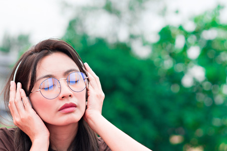 Portrait woman listening to music with nature background.の写真素材