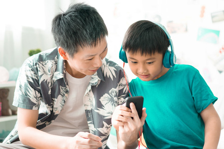 Father with son listening to music on bed in bedroom