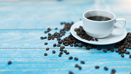 Coffee cup with coffee beans on vintage wooden table.