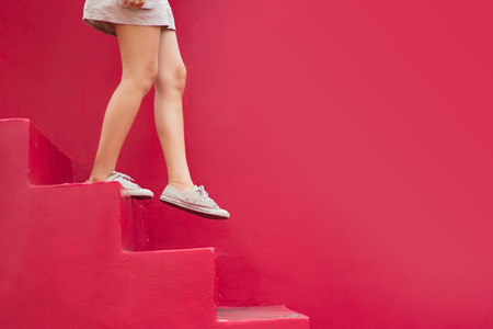 Legs of woman walking down red stair with copy space on red background.の写真素材