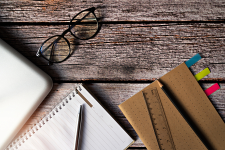 Eye glasses and stationery with laptop on wooden table.の写真素材