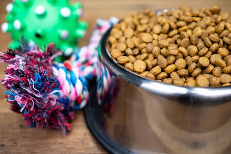 Dry food in stainless bowls on wooden table.  Pet supplies concept