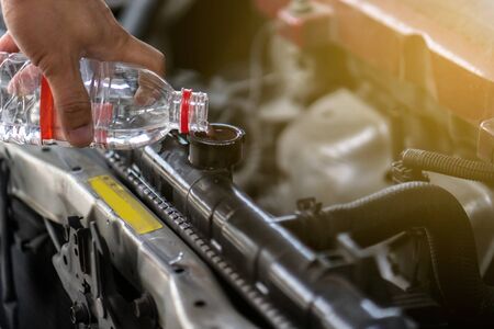 Hand pouring water for radiator in car.  Because of the heat is due to some deterioration.の写真素材