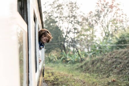 Happy woman looks out from window traveling by train in Thailand.  Blurred  photo