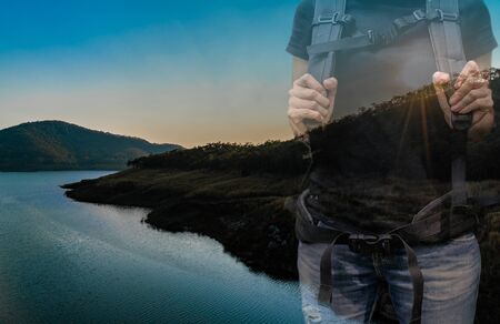 Double exposure photo of sunset with mountain and backpacker hiking at the forestの写真素材