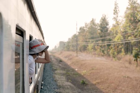 Woman looks out from window traveling by trainの写真素材