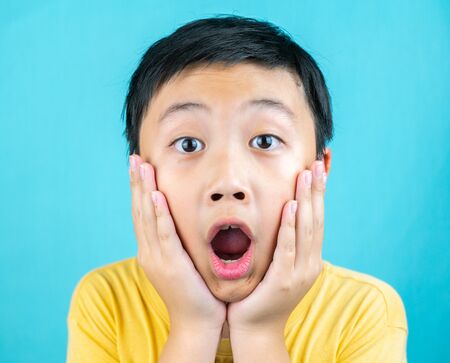 Little boy make surprised face on blue background