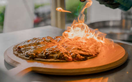 Hand is torch cheese for food at restaurantの写真素材