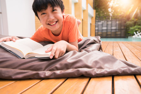 A Boy smiling with a book on wooden table.  Learning at homeの写真素材