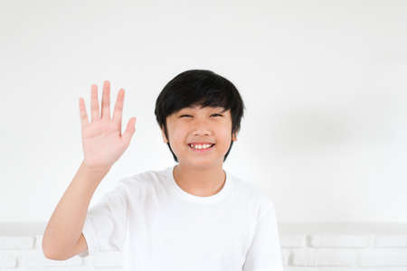 Portrait Asian boy waving hand for greeting on white background