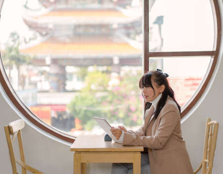 Asian business woman sit using tablet for order and working at restaurantの写真素材