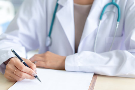 Female doctor writing on medical paper at a clinic.の写真素材