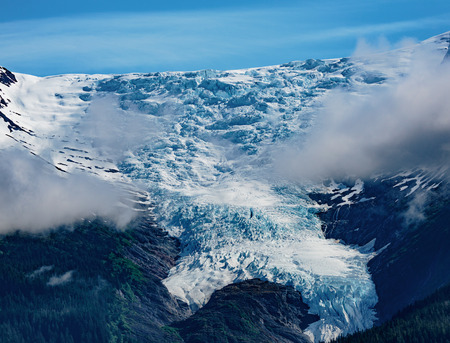 Tracy Arm Fjord, AK, USA - May 27, 2016:  Closeup  of one of the many mountain peaks saddles seen while cruising the Tracy Arm Fjord, in Alaska.  Blue sky, low clouds, crisp snow and ice reflections of the Tongass National Forest.のeditorial素材