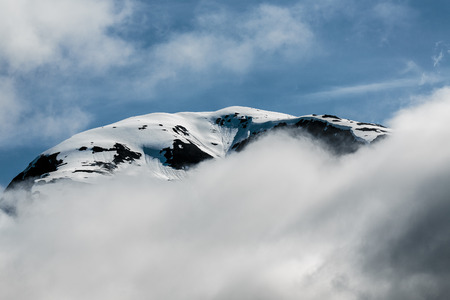 Tracy Arm Fjord, AK, USA - May 27, 2016:  Closeup  of one of the many mountain peaks seen while cruising the Tracy Arm Fjord, in Alaska.  Blue sky, low clouds, crisp snow and ice reflections of the Tongass National Forest.のeditorial素材