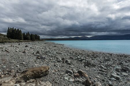 Turquoise glacier lake with beach and cloudy sky during rainy daysの写真素材