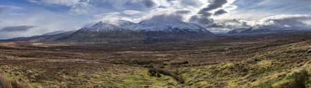 In the middle of scottish highlands with snowy mountains panoramaの写真素材