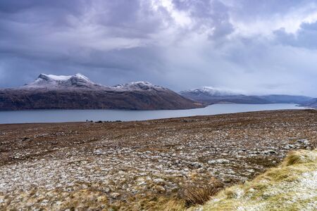Blue lake and meadow in front of the snowy mountains