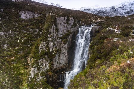 Beautiful waterfall in a mountains with green grass aroundの写真素材