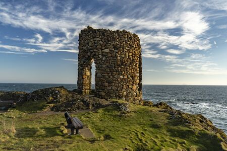 Old stone architecture with green rocky coast a the edge of oceanの写真素材