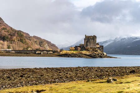 Old castle at the edge of lake with with stone bridge and mountainsのeditorial素材
