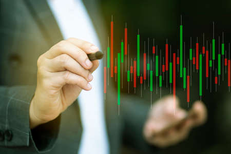 Closeup at hand Businessmen are viewing stocks online. He analyzed the investment from the graph shown. He uses the pen to point to the graph to determine whether or not to invest well.の写真素材