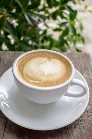 Cup of hot coffee latte with latte art on wooden tableの写真素材