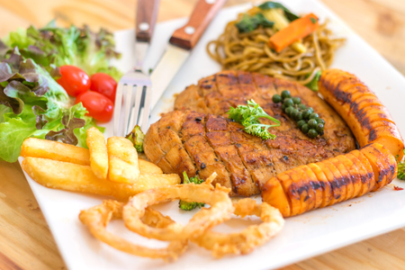 Chicken Steak serve with sausage,onion ring,french fried, salad and spaghetti basil sauceの写真素材
